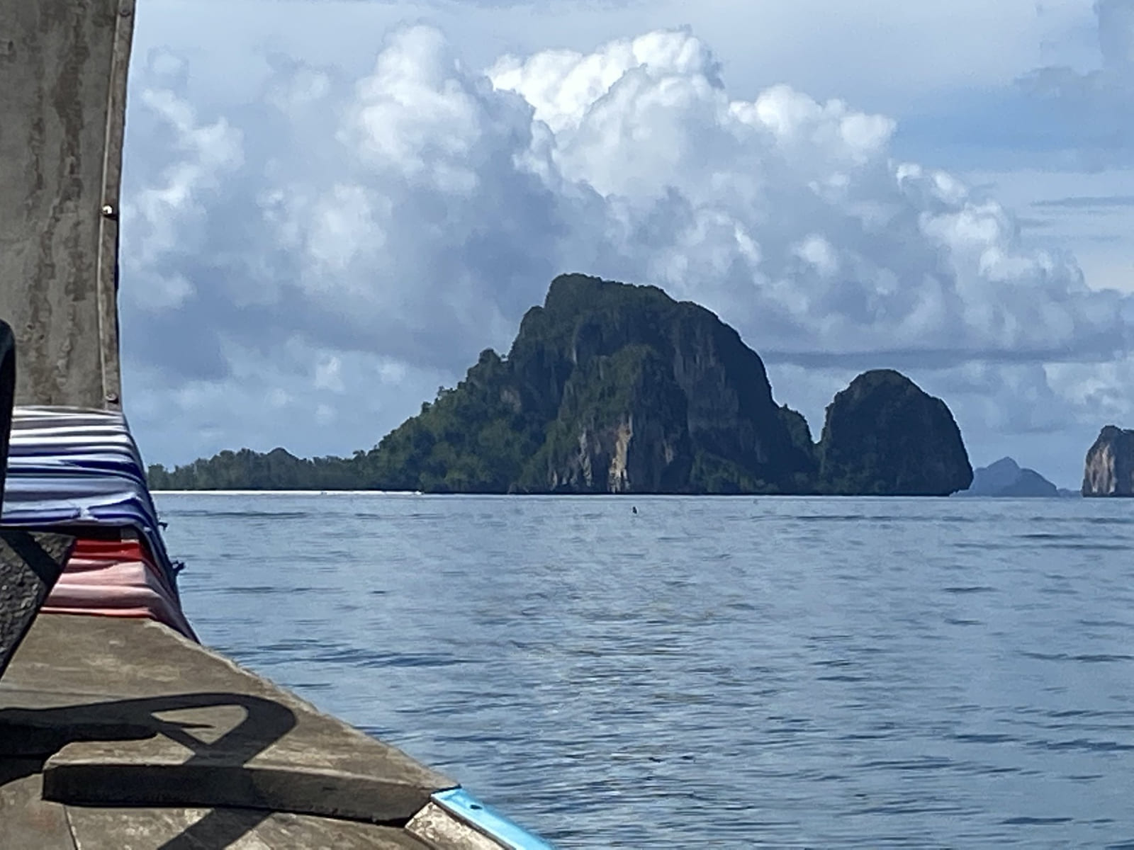 A longtail boat below limestone cliffs