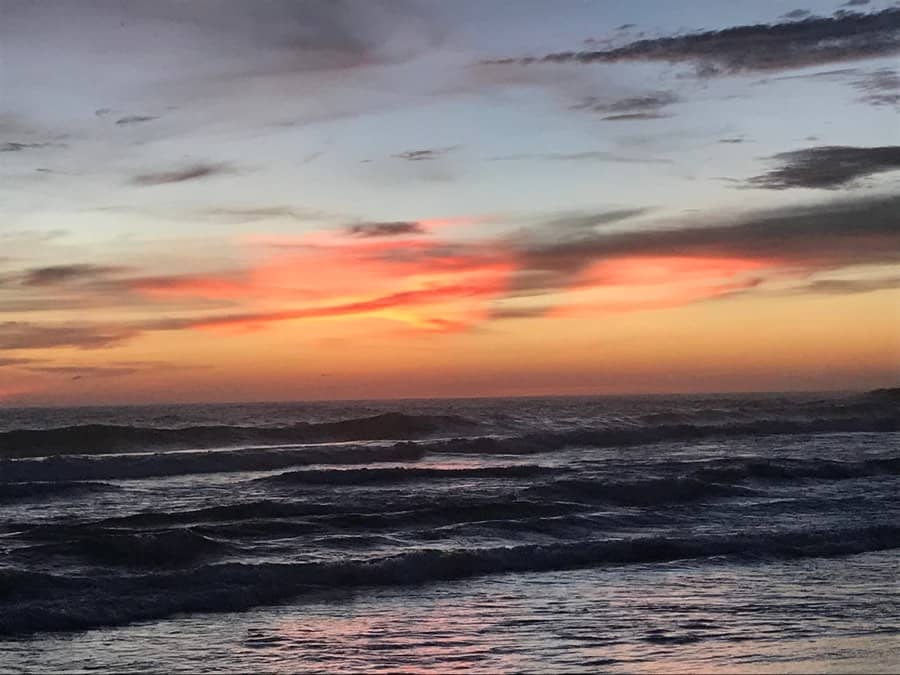 Coral-coloured clouds over the surf at sunset