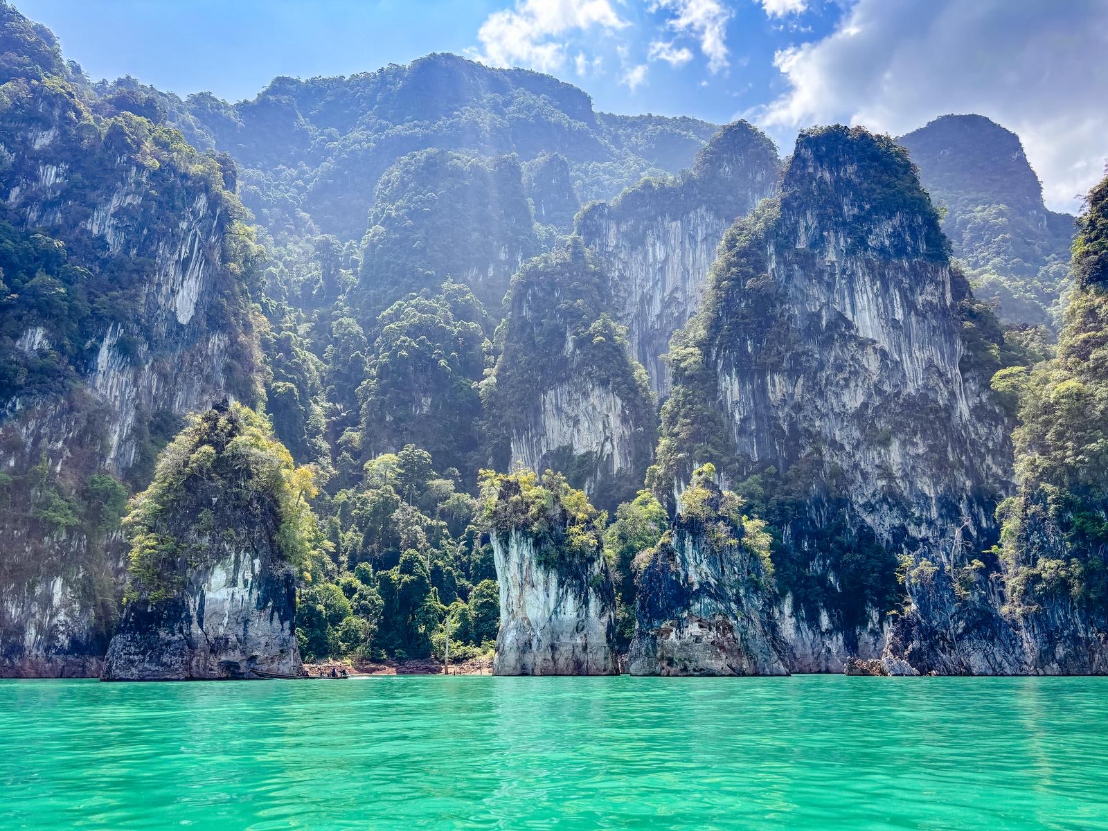 Sheer jungle-topped karst cliffs rising from the emerald water of Cheow Lan Lake