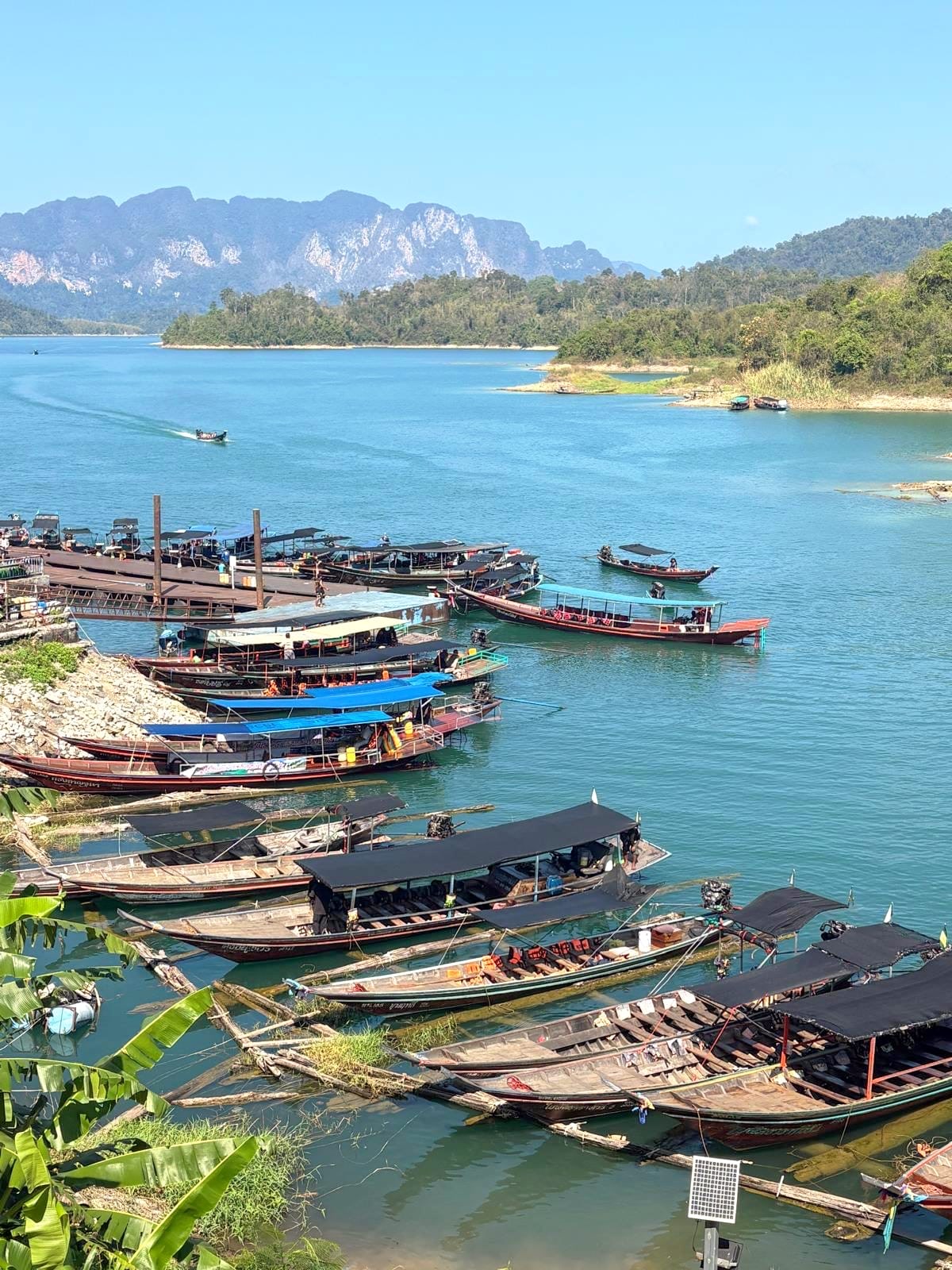 Many longtail boats moored at the launch pier on the blue reservoir