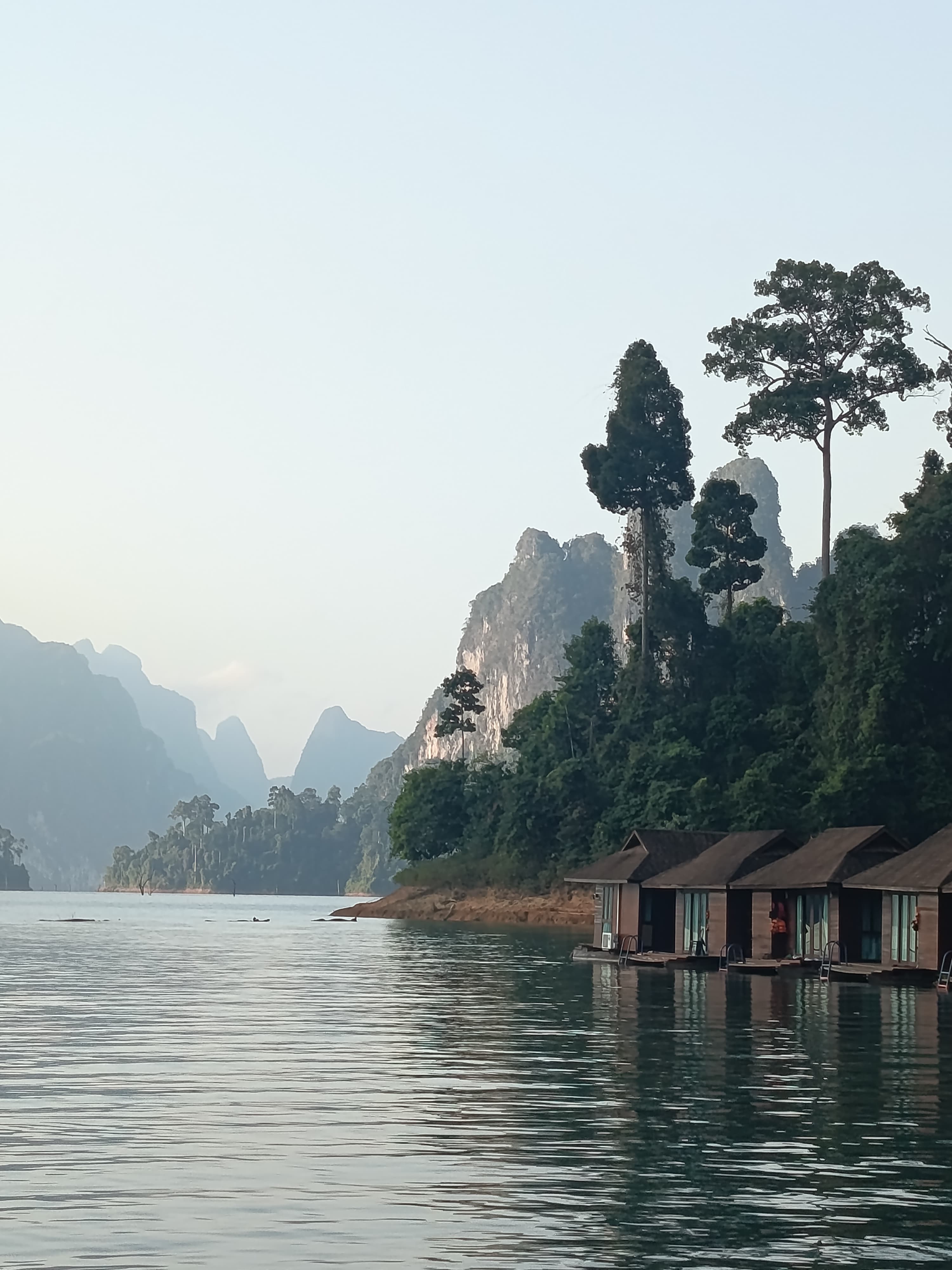 Misty dawn over still water, karst silhouettes and raft houses