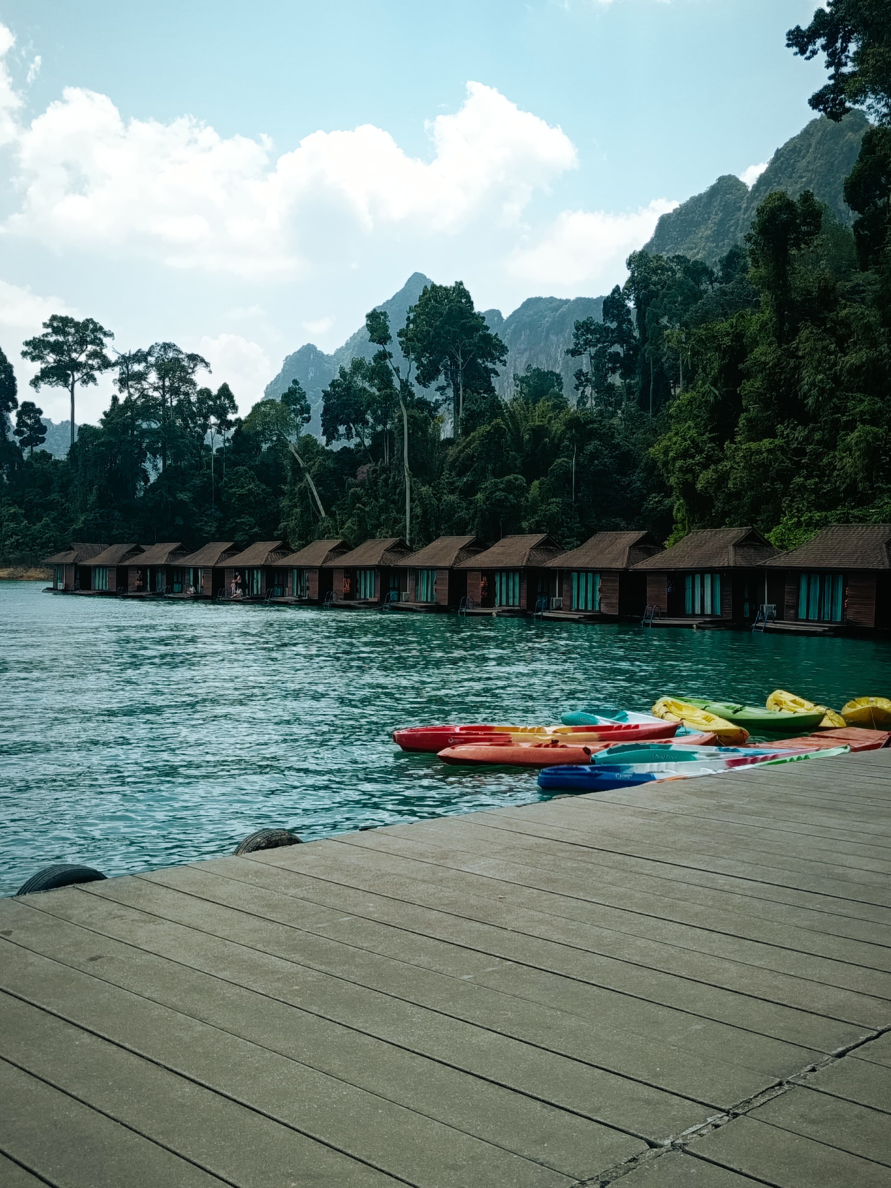 Raft bungalows with red, yellow and blue kayaks at the dock