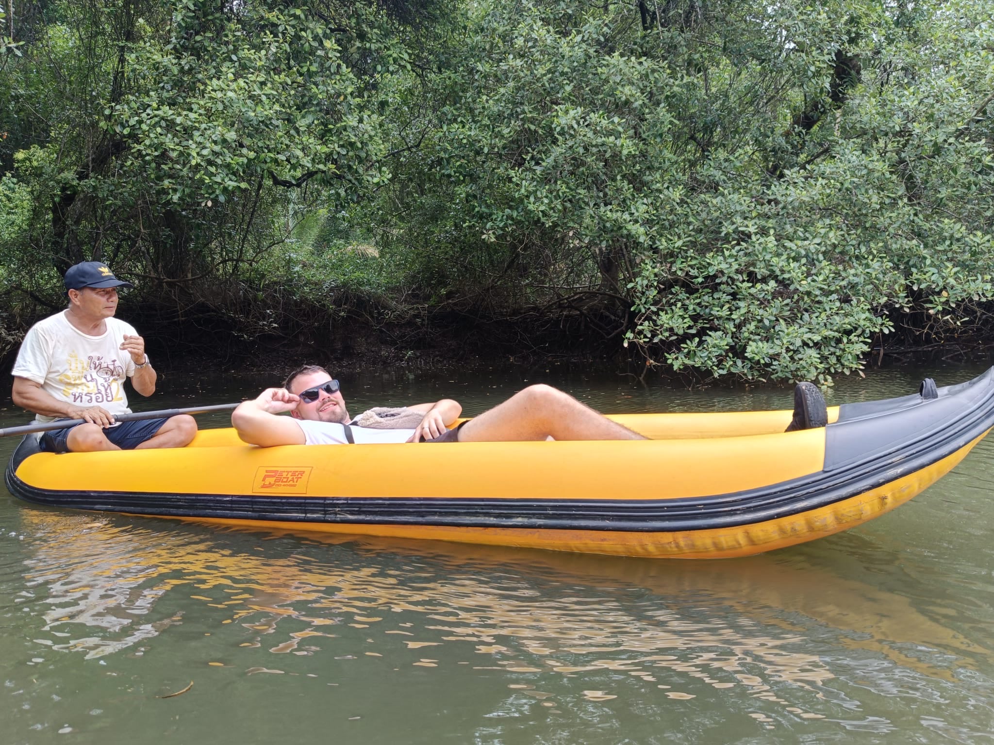 A yellow inflatable kayak on the Sok River, a guest and a local paddler