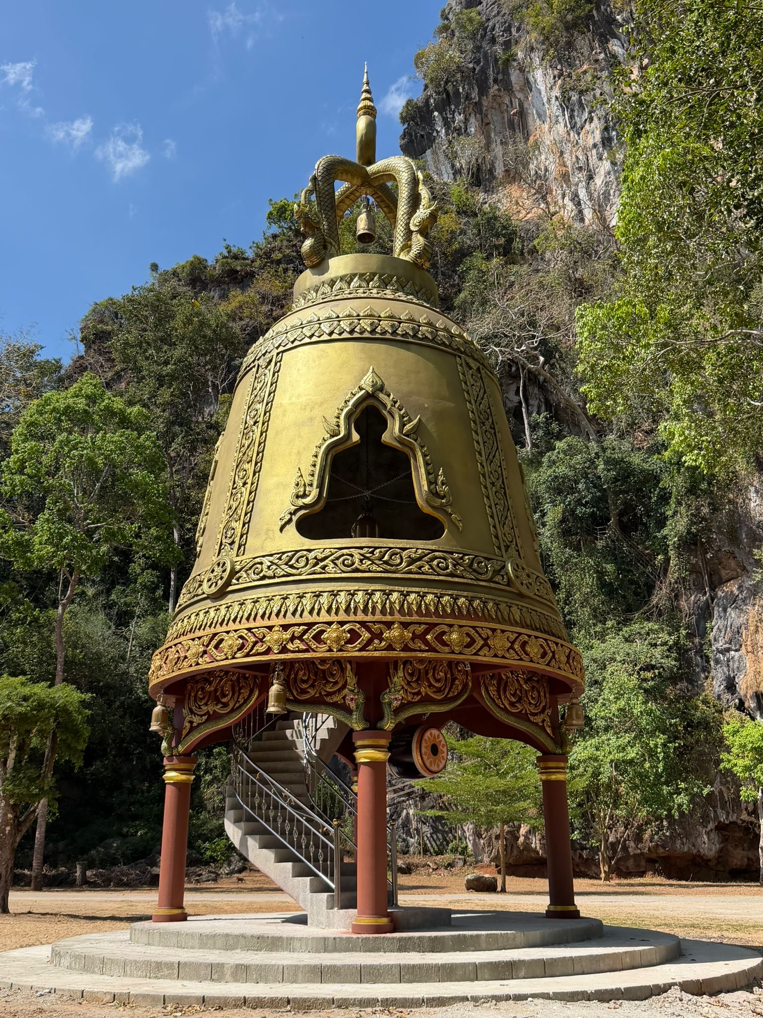 A large bronze temple bell against the karst