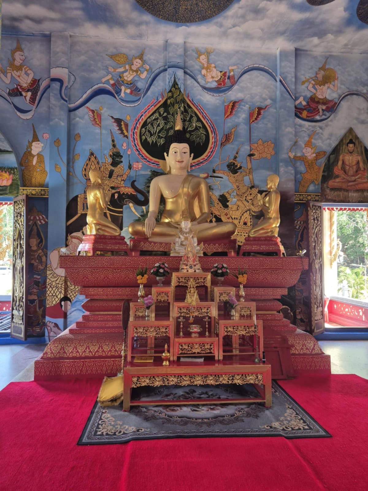 The main shrine — a gold seated Buddha under a blue cloud-painted ceiling